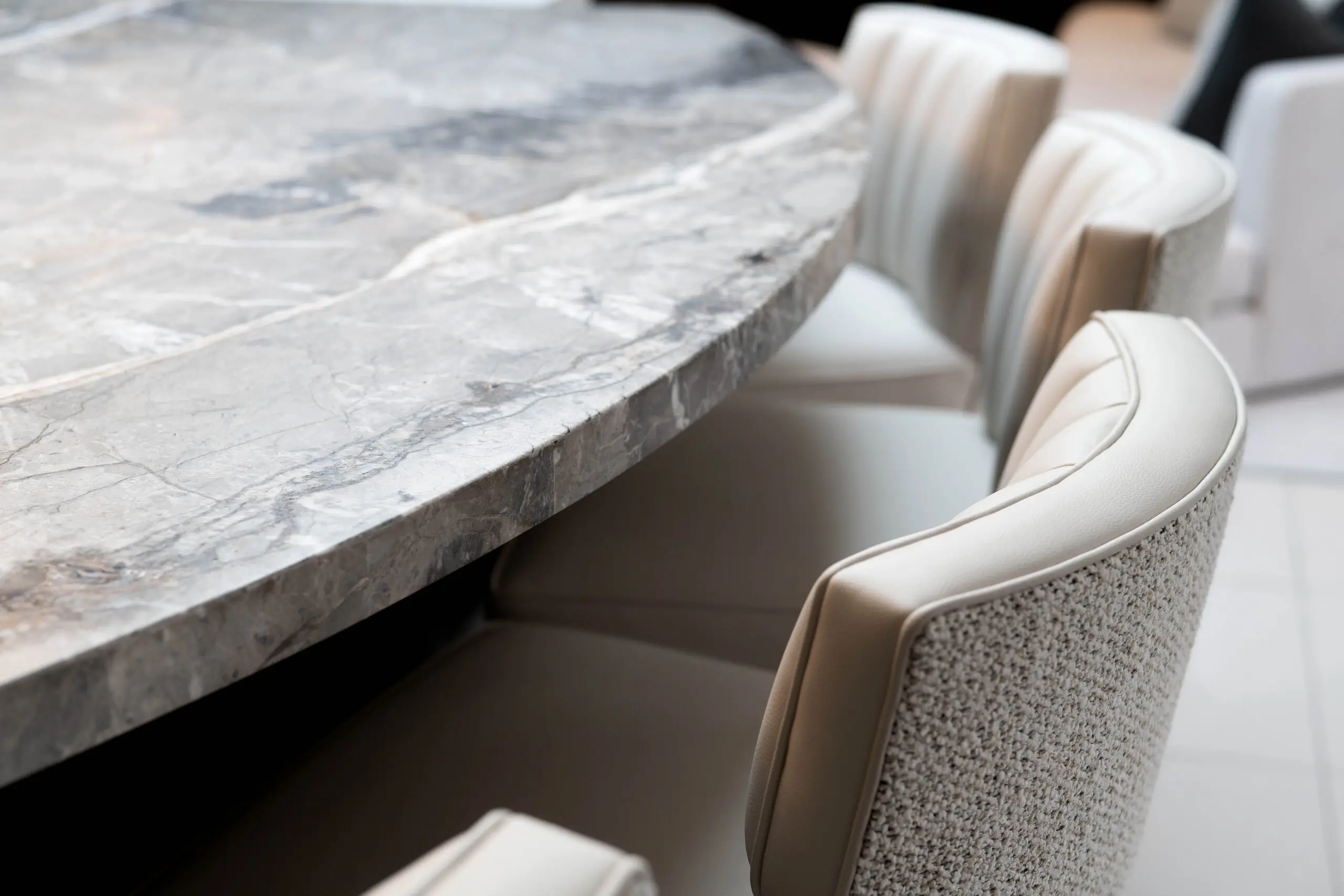 Elegant round marble table surrounded by plush beige chairs, creating a sophisticated and inviting dining atmosphere.