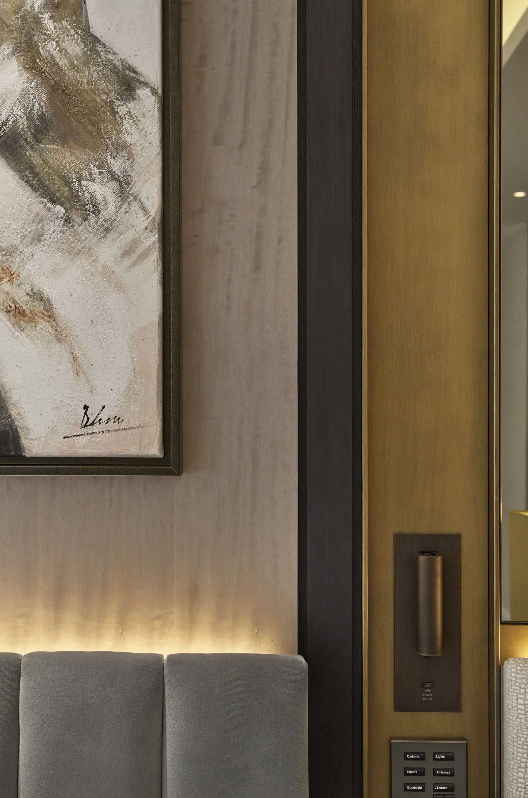A modern interior featuring an abstract painting on a textured wall, with soft lighting and sleek control panel, creating a cosy, upscale ambiance.